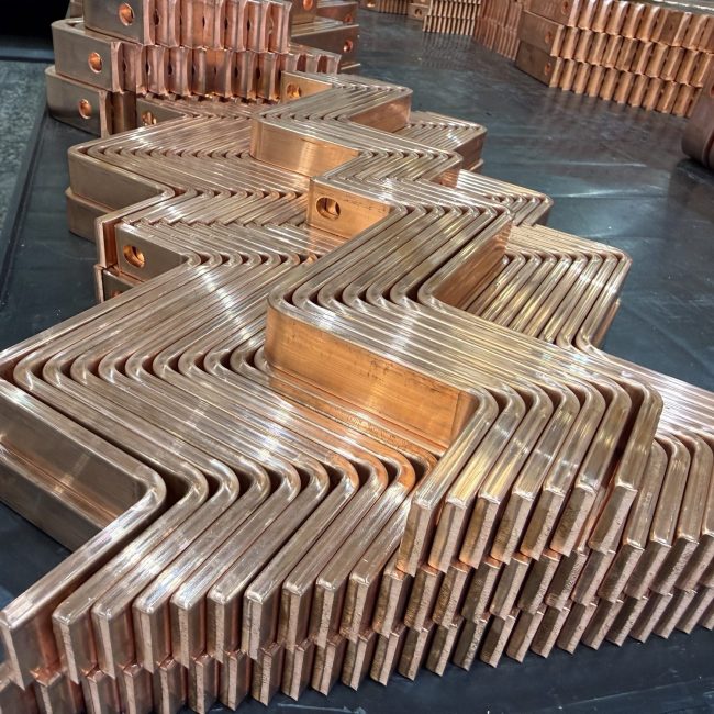 Bent copper busbars stacked after forming at ILF